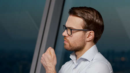 Portrait of a thinking young man in the evening office, close-up