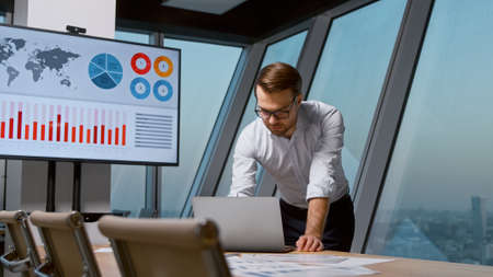 Young businessman working with laptop in meeting room at the windowの写真素材