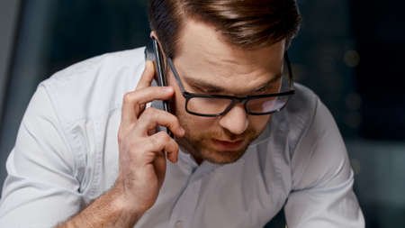 Young man talking on the phone after hours in the officeの写真素材