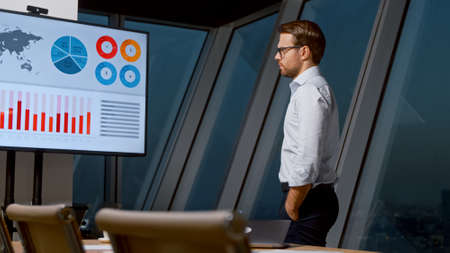 Young professional man looking at screen in meeting room in the eveningの写真素材