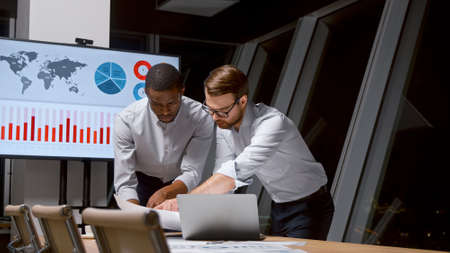 Two businessmen working in a team doing analytics in the office after a working dayの写真素材