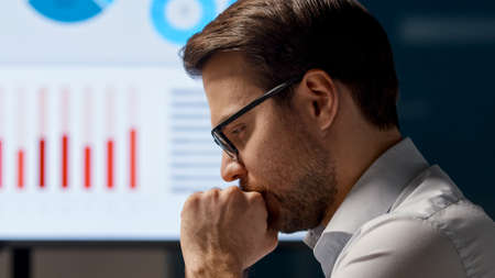 Young businessman working with a computer against the background of graphs and diagrams in the officeの写真素材