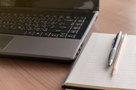 Laptop with a pen and notebook on the tableの写真素材