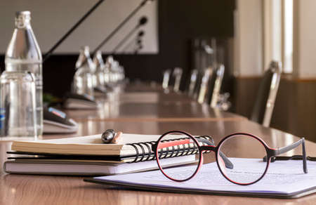 Glasses, pen, pencil, and notebooks in meeting roomの写真素材