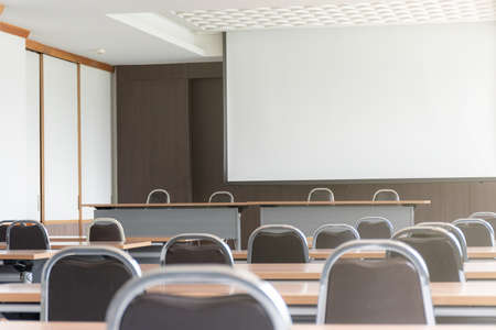 Seminar room with a speaker table in the middle of the stage and white screenの写真素材