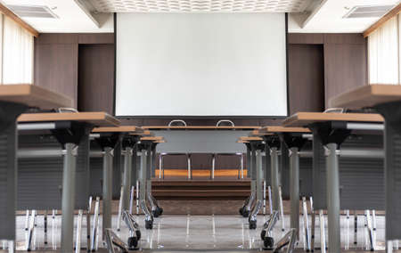 Seminar room with a speaker table in the middle of the stage and white screenの写真素材
