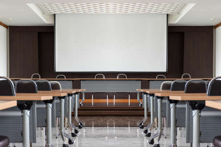 Seminar room with a speaker table in the middle of the stage and white screenの写真素材