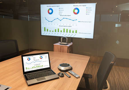 Close up laptop on table with Presentation meeting on television in Video conference meeting room (Work from home Concept)の写真素材