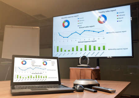 Close up laptop on table with Presentation meeting on television in Video conference meeting room (Work from home Concept)の写真素材