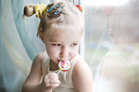 Sad toddler girl with candyの写真素材