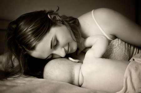 young beautiful mother lies near her newborn baby with eyes closedの写真素材