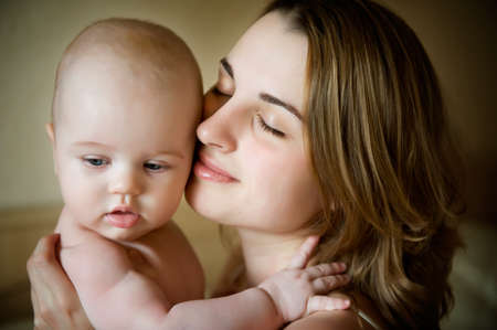 young beautiful mother holding infant baby with eyes closedの写真素材