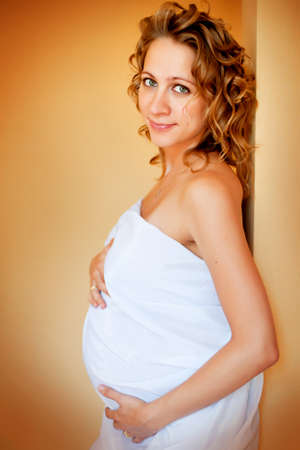 Beautiful young pregnant woman standing near wallの写真素材