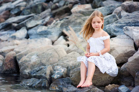 Lonely beautiful girl sitting on stone sea shore and thinking Lonely beautiful girl sitting on stone sea shore and thinking