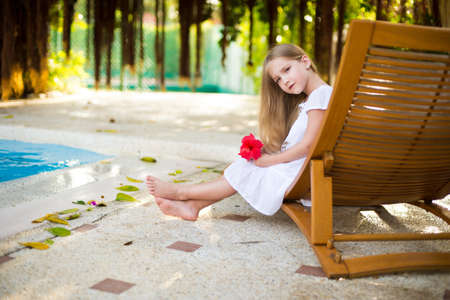 Adorable european toddler girl in tropical garden near swimming poolの写真素材