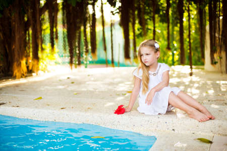 Adorable european toddler girl in tropical garden near swimming poolの写真素材