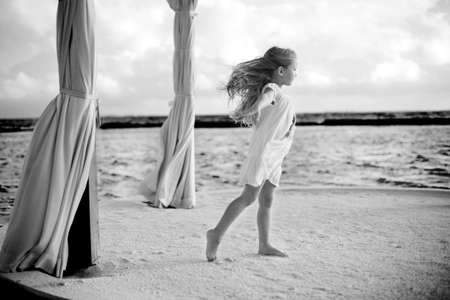 Black and white photo of toddler european girl on the sea pier against windの写真素材