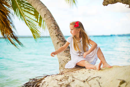 Adorable lonely girl sitting on beach in tropical island plays with sandの写真素材