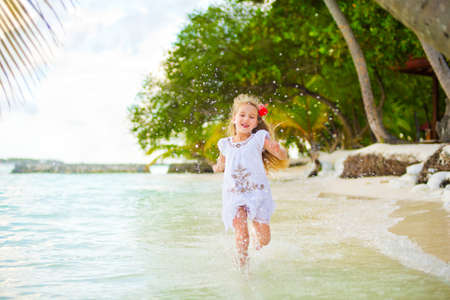 Happy european girl running in water on seashore of tropical islandの写真素材