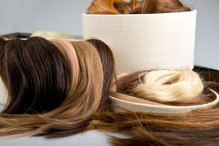 Locks of faux hair for beauty salolon different colors and structure in box  Blond, red and brunette on gray backgroundの写真素材