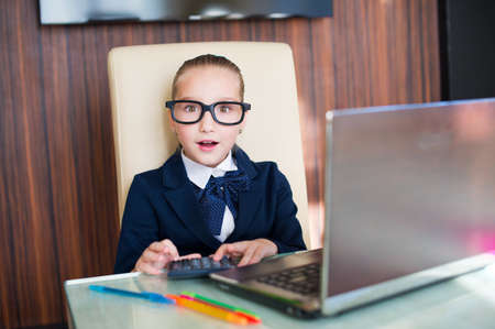 Young business lady girl in glasses surprised at the table with laptop computer and calculatorの写真素材