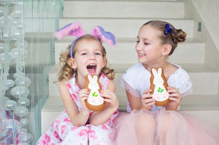 Two cute caucasian toddler sister girls in fancy bunny ears having fun and celebrate Easter and...