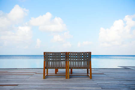 Lonely armchair for two near swimming pool with view on turquoise oceanの写真素材