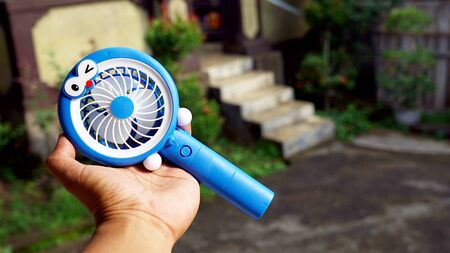 Close up hand holding a portable fanの写真素材