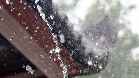 Close up of rain water falling from the roof of the house