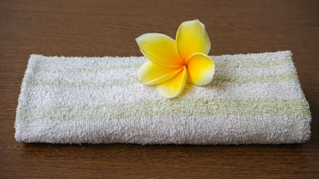 Close up of yellow frangipani flowers and towels on a wooden tableの写真素材