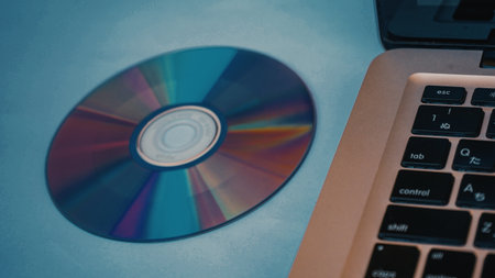 Laptop and compact disc on blue background, vintage color tone.の写真素材