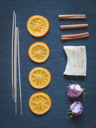 Aromatic composition of caramelized oranges, incense, soap, cinnamon and dried flowers on a dark blue background. Top view. Low contrast tonedの写真素材