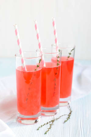Pink fruit lemonade in tall glasses with  sprig of thyme. Selective focusの写真素材