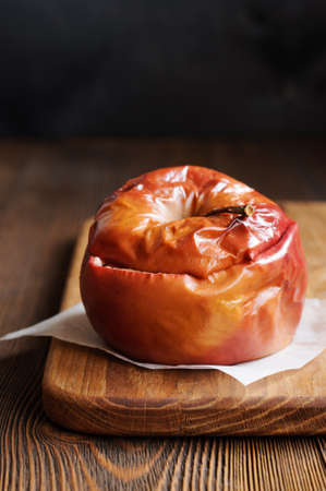 Single apple baked with honey on wooden cutting boardの写真素材