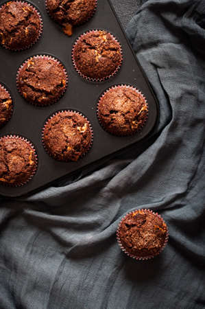 Chocolate muffins in baking mold on background of blue cheesecloth. Flat layの写真素材