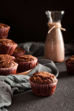 Chocolate muffins and cocoa drink with chia seeds in glass bottle on dark background. Low keyの写真素材