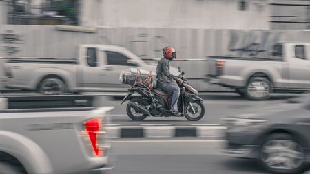 a scooter driver through the streets of bangkok, thailandのeditorial素材