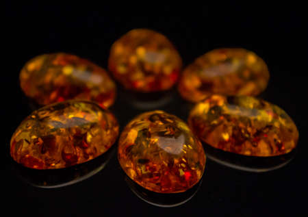 Artificial amber polished cabochons on a black background macro