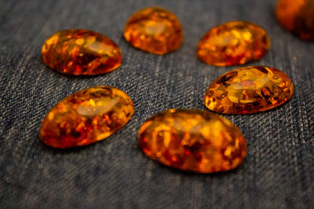 Artificial amber polished cabochon on a blue background macro