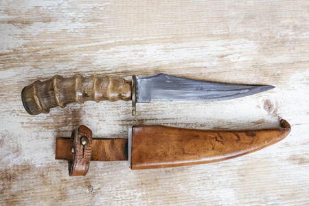 Old hunting knife on a wooden background. The handle is from horn of animalの写真素材