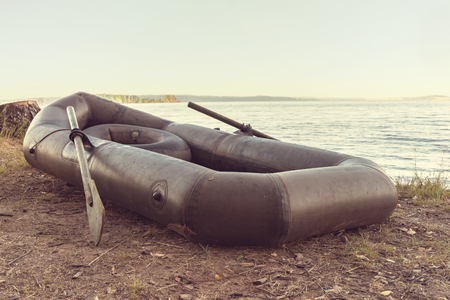 Black rubber boat with oars on the shore.の写真素材