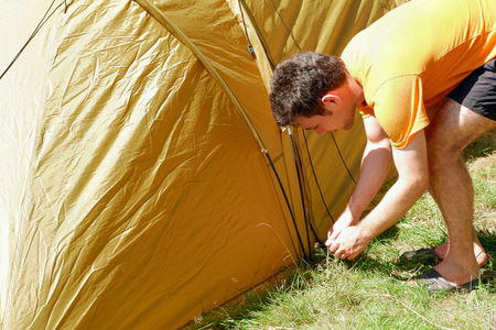 Young man set up a tent. Preparation for outdoor recreationの写真素材