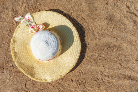 Women's hat on the sandy beach. Top view. Background with copy space