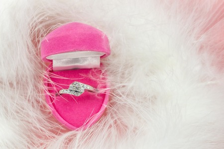 Engagement ring in the pink heart box with on a white fluffy background, top view. Copy spaceの写真素材