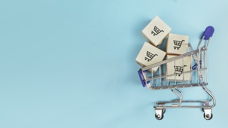 Boxes in a shopping cart on blue background. Concept: online shopping, e commerce and delivery of goods. Copy space