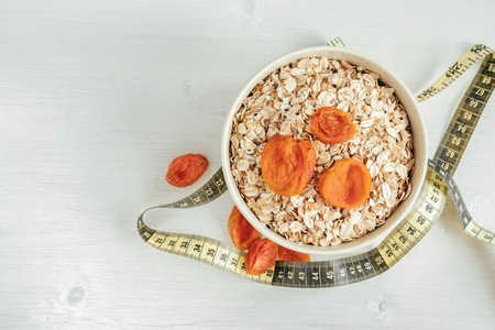 Cereal flakes with dried apricots and measuring tape. Top viewの写真素材