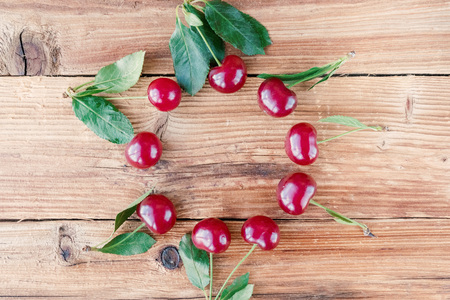 Fruit background. Ripe cherry with green leaves on wooden background.の写真素材