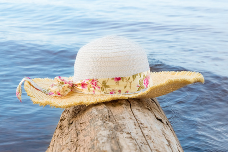 Women's hat with wide brim on a log on the waterの写真素材