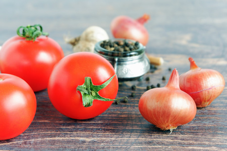 Tomatoes, onions, garlic and black pepper on wooden backgroundの写真素材