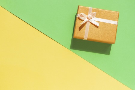 Gift box with bow on yellow and green background. Top viewの写真素材